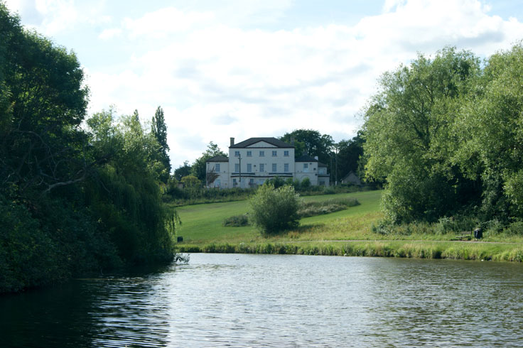 A lake in a park, with a large building in the background.